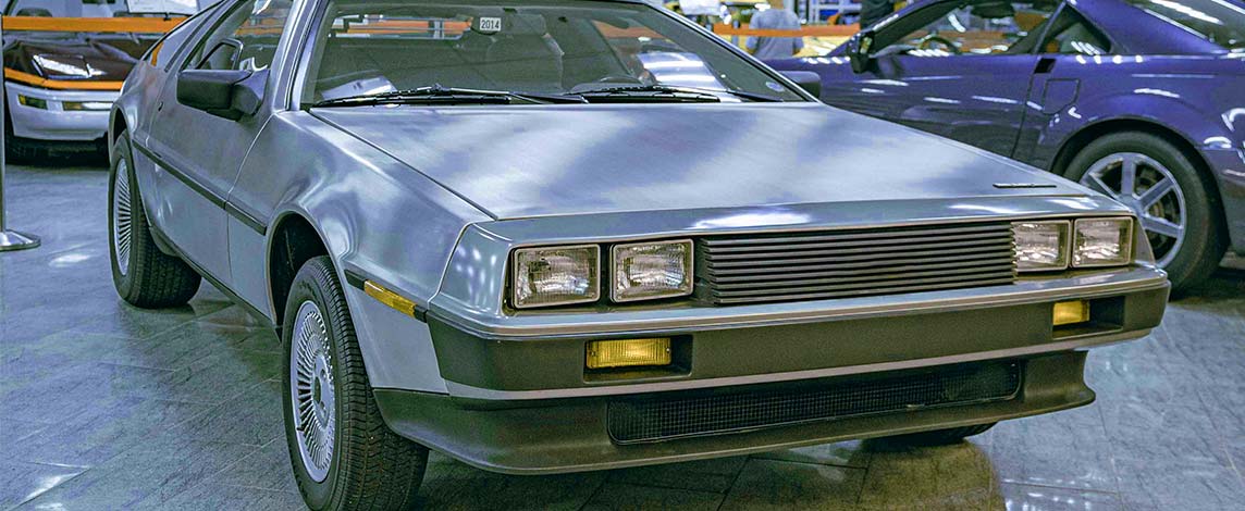 A gray 1980s Delorean car sits on a showroom floor.